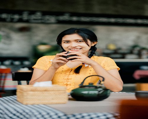 Seseorang sedang tersenyum sambil menikmati secangkir teh